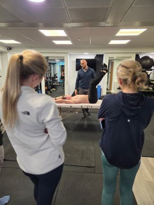 DNS instructor demonstrating supine leg assessment to group of attendees