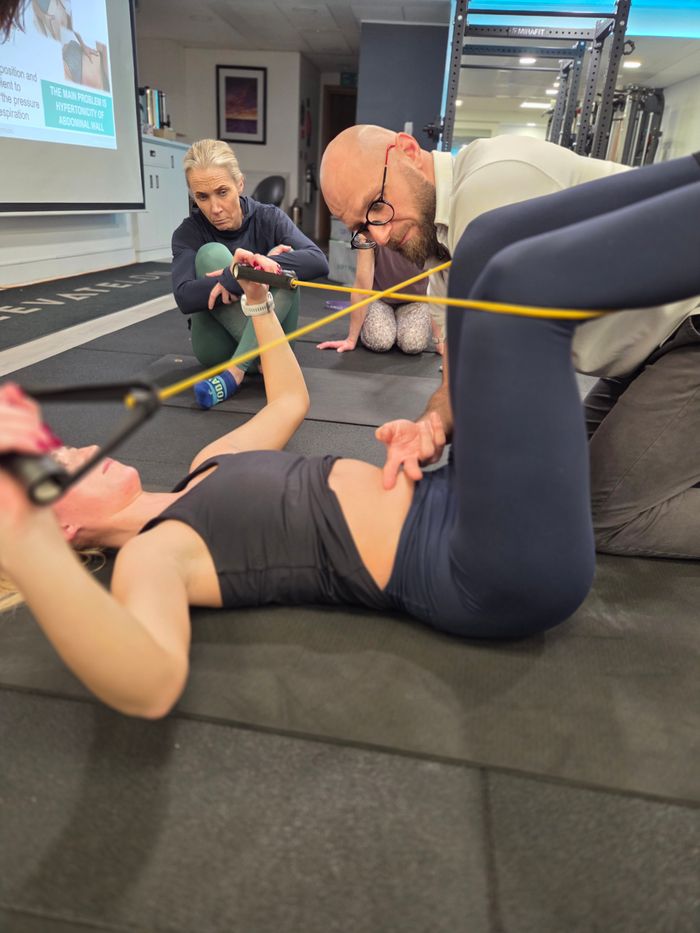 Supine resistance band exercise during DNS Exercise Part II course at Elevate LDN