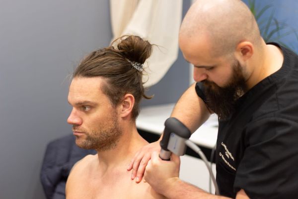 Chiropractor delivering shockwave treatment at London Healthcare Clinic, the clinic Elevate LDN's studio sits inside