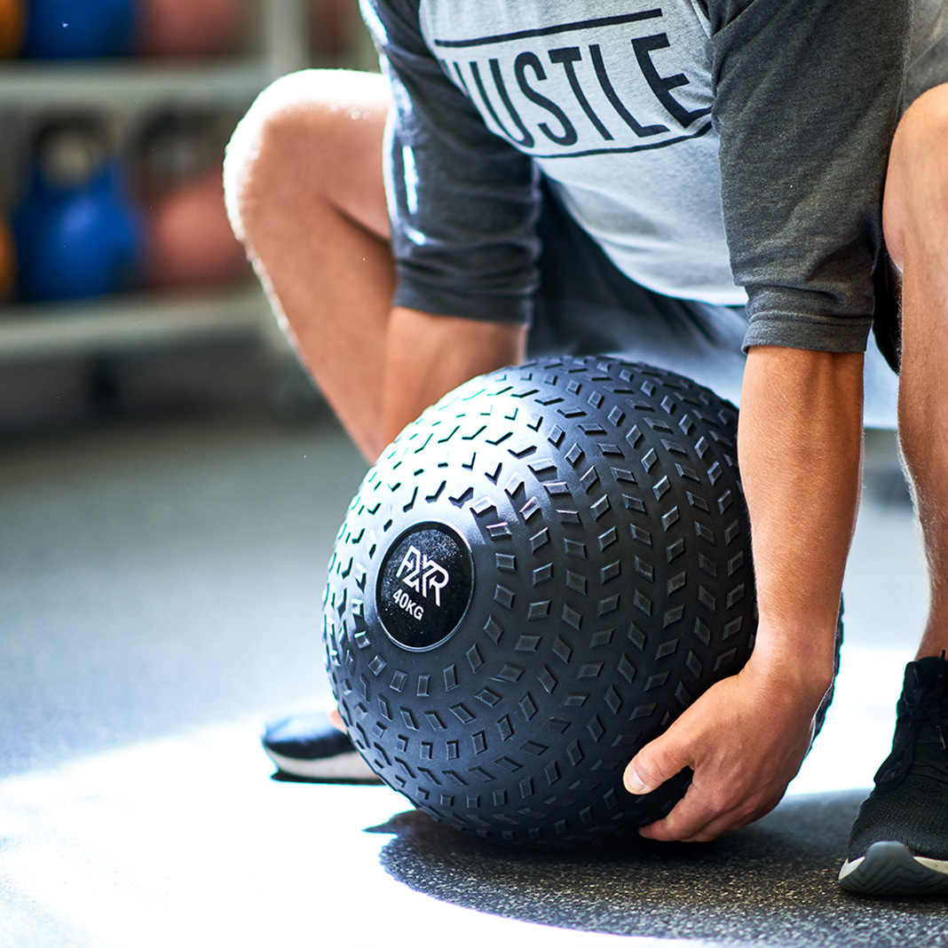 Man lifting heavy weighted ball in personal training studio