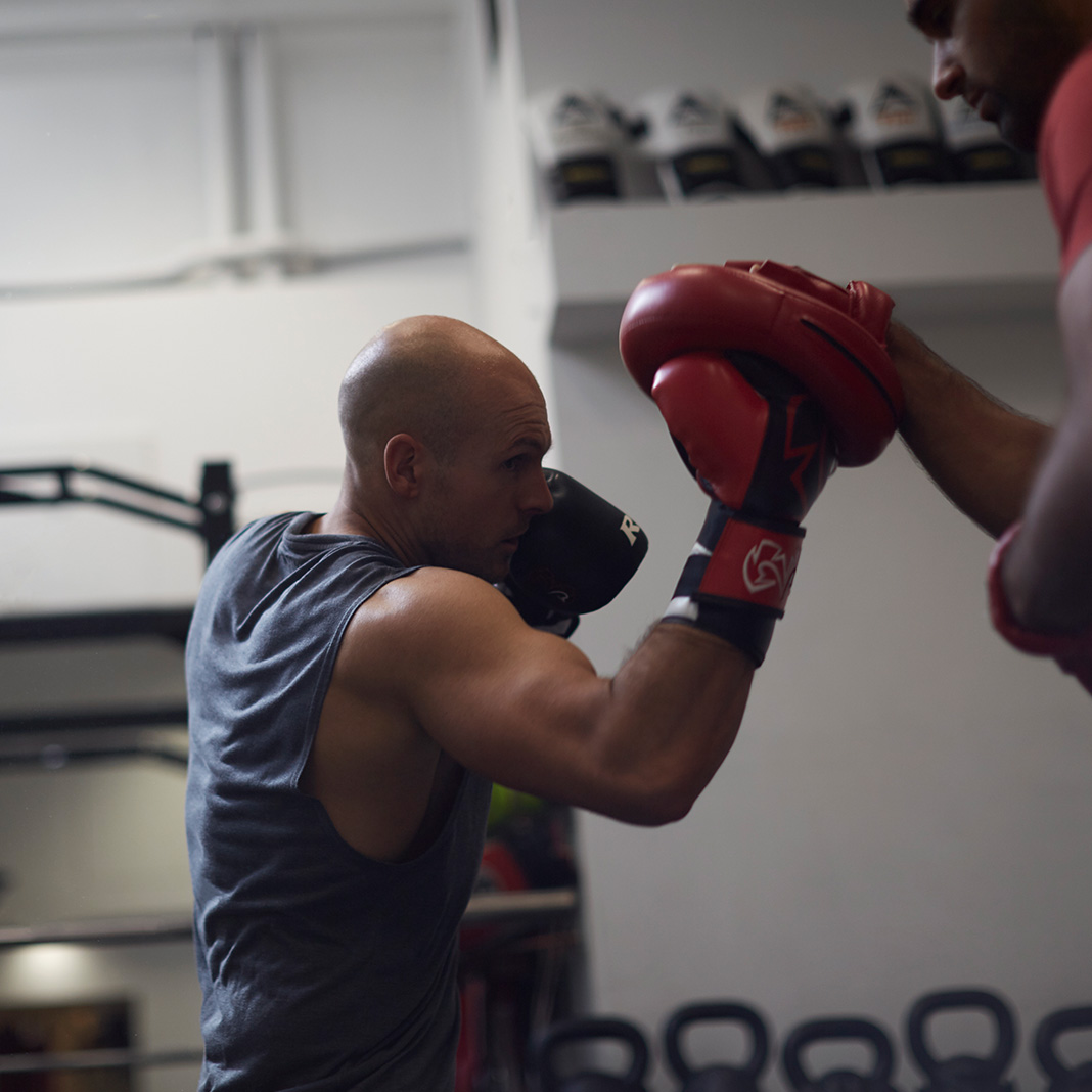 Man boxing on pads with a personal trainer