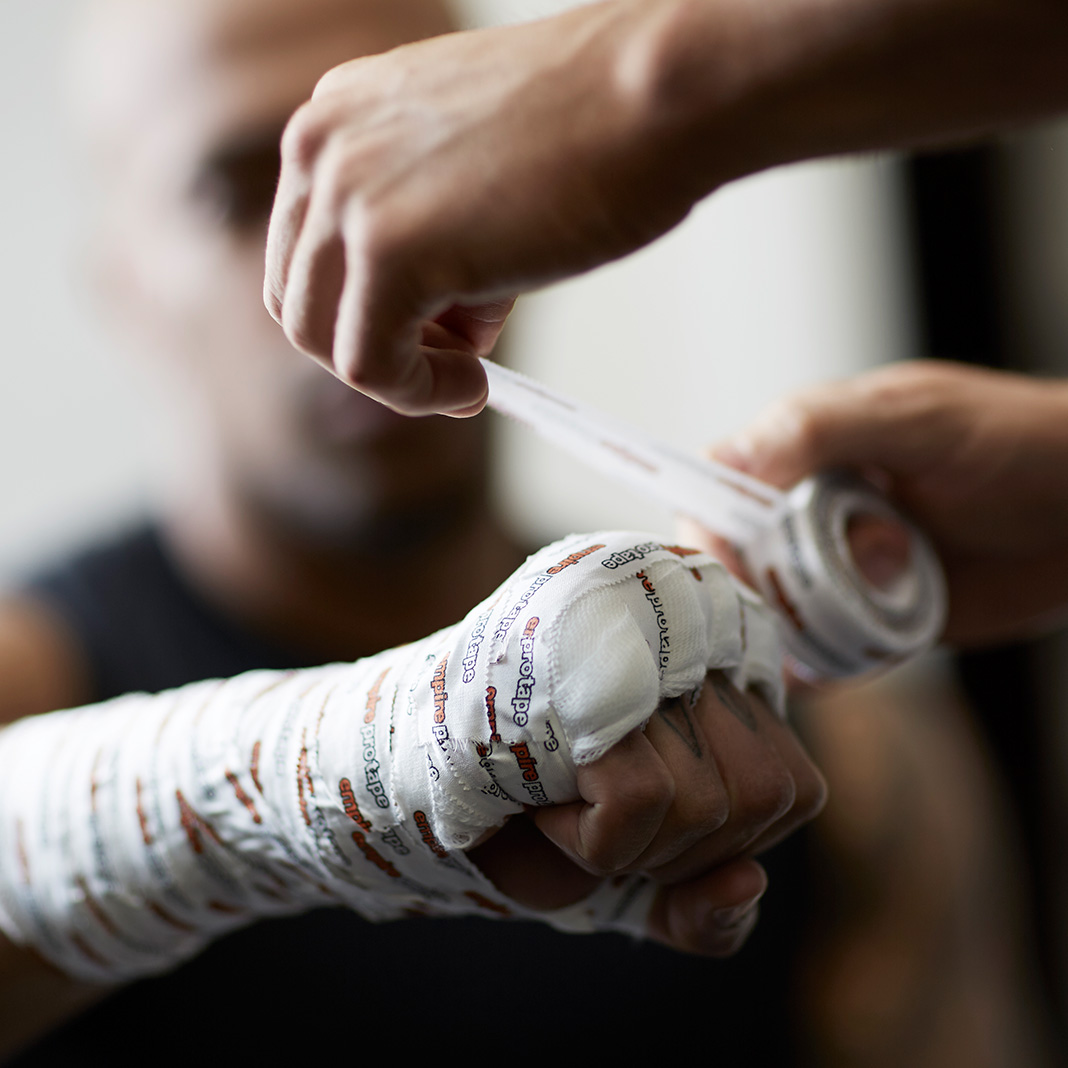 Trainer wrapping a boxer's fist with tape